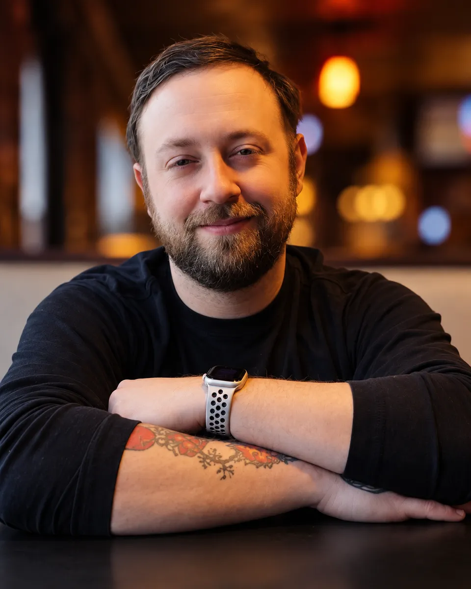 Tim Long, owner of Warped Web Studio, sitting at a table with his arms folded.